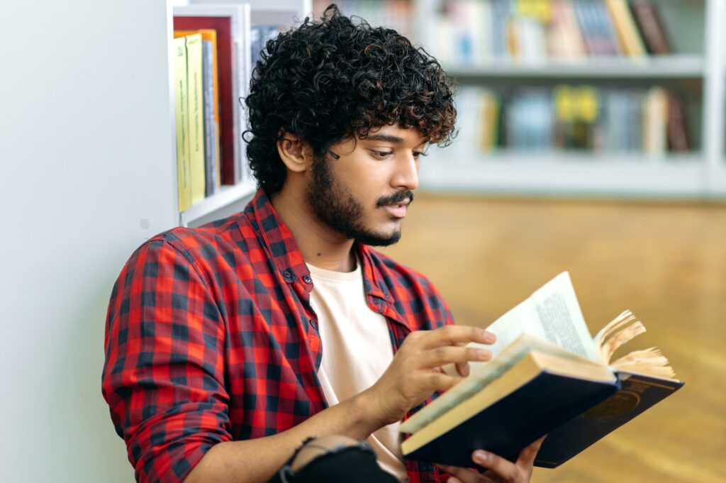 Book reading. Focused clever indian or arabian university or college male student, sitting in a