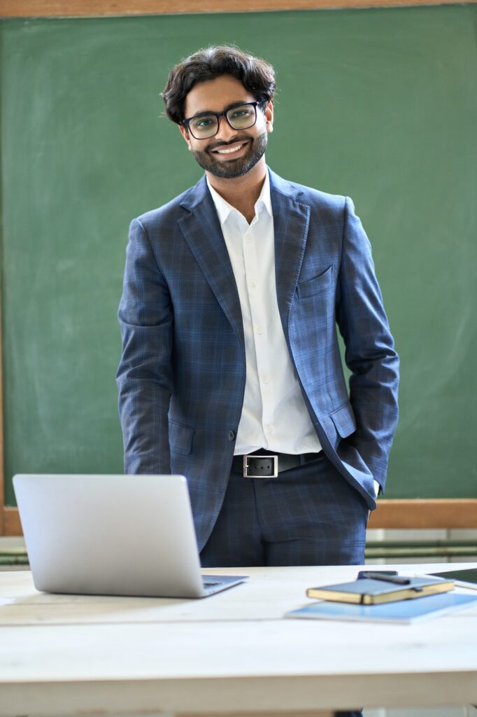 Smiling young indian business man wearing suit standing in office. Portrait