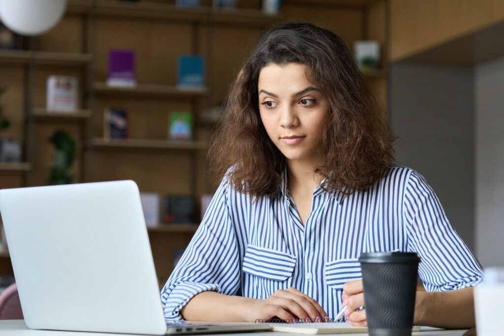 Young latin indian student using laptop watching online virtual training.